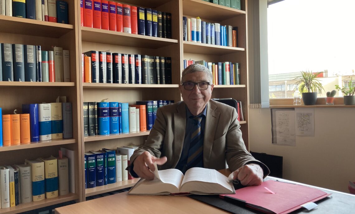 Rechtsanwalt Herbert Emrich sitzend vor einem Bücherregal